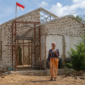 Ibu Fatiha berdiri di depan rumahnya di Desa Ambunten Barat, Sumenep, yang masih dalam proses renovasi. Rumah tersebut sebelumnya berada dalam kondisi memprihatinkan dan nyaris roboh sebelum mendapat bantuan renovasi melalui inisiatif BAZNAS Sumenep. Di atas bangunan itu, bendera Merah Putih tetap berkibar sebagai simbol kecintaan Fatiha terhadap Tanah Air.